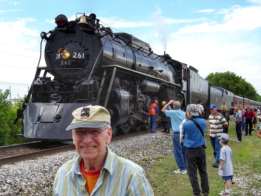 Wil Bloy standing in front of a steam locomotive as it's parked on the track.
