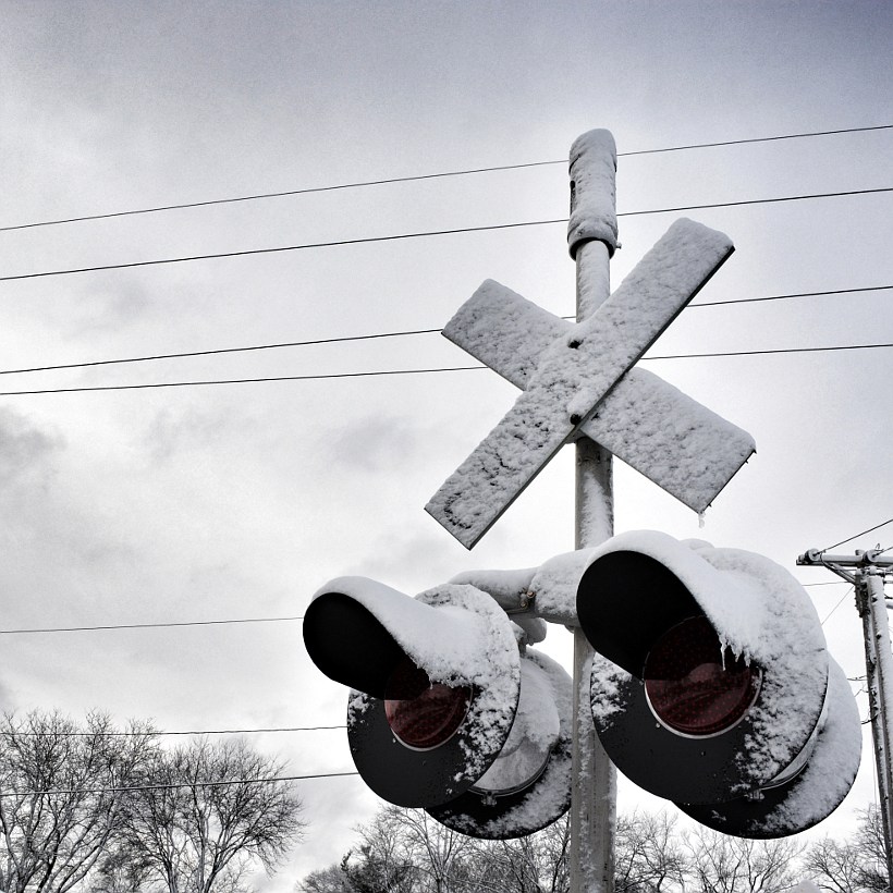 Snow and ice covering a railroad crossing sign