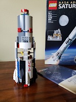 Lego pieces from 2 bags forming the first stage of a Saturn V rocket