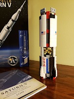 Lego pieces from 3 bags forming the first stage of a Saturn V rocket