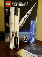 Lego pieces from 4 bags forming the first stage of a Saturn V rocket