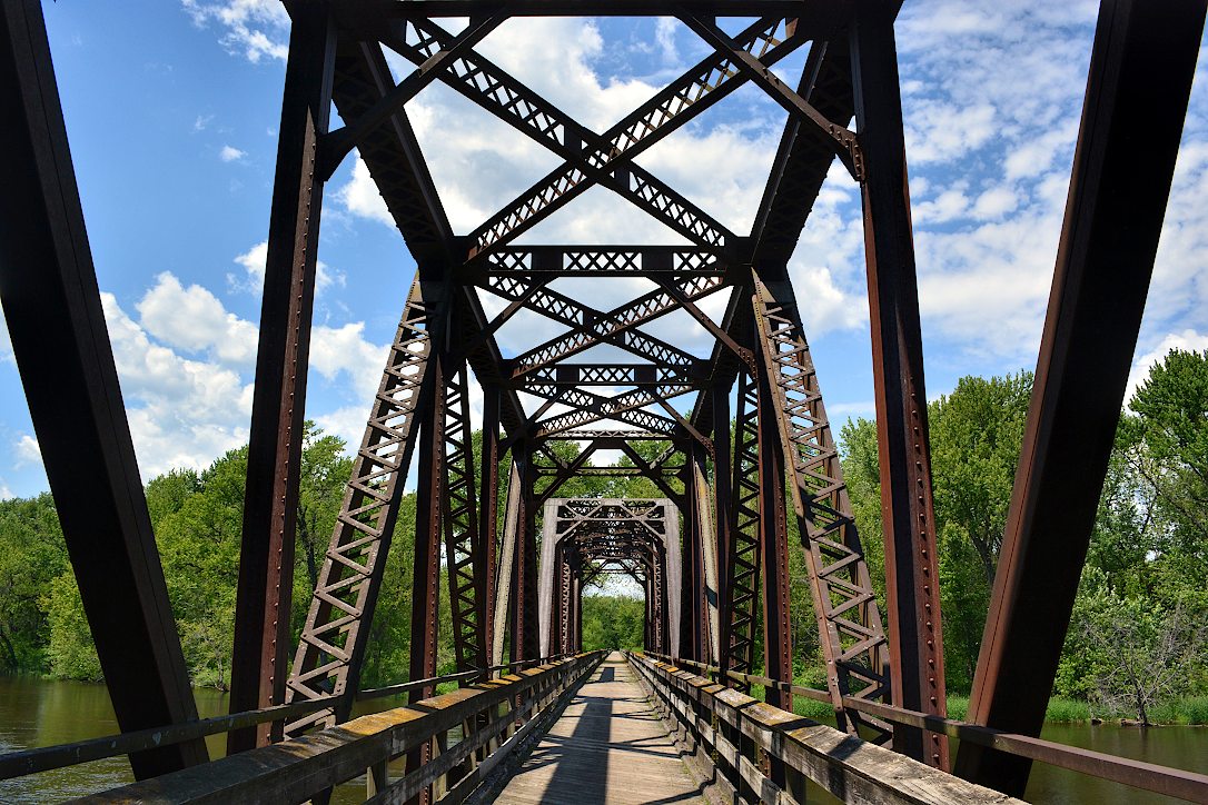 View of a recreational trail leading into the distance, through the many girders of a bridge