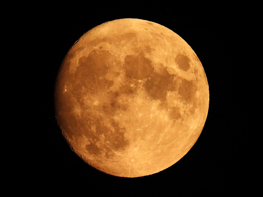 An orange tinted full moon in a dark sky