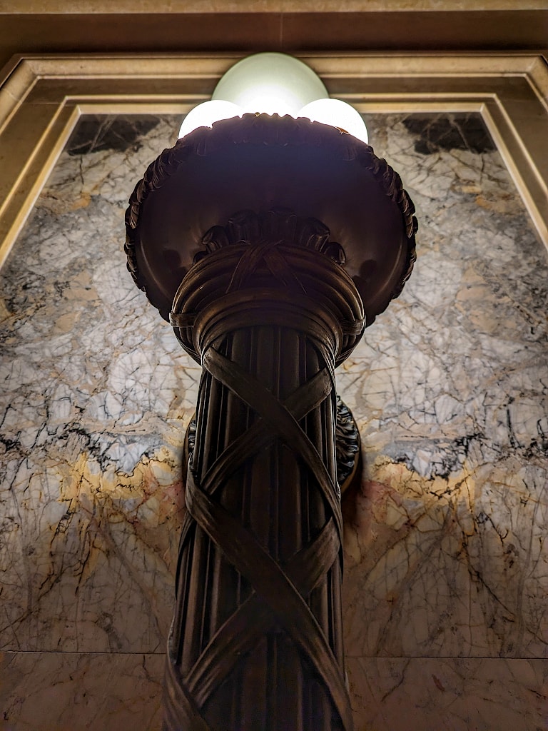Looking up along the wall at a large, ornate wall sconce.