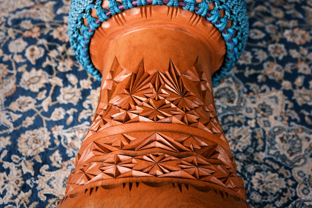 The base of a djembe drum with ornate, geometric shapes carved in the wood.